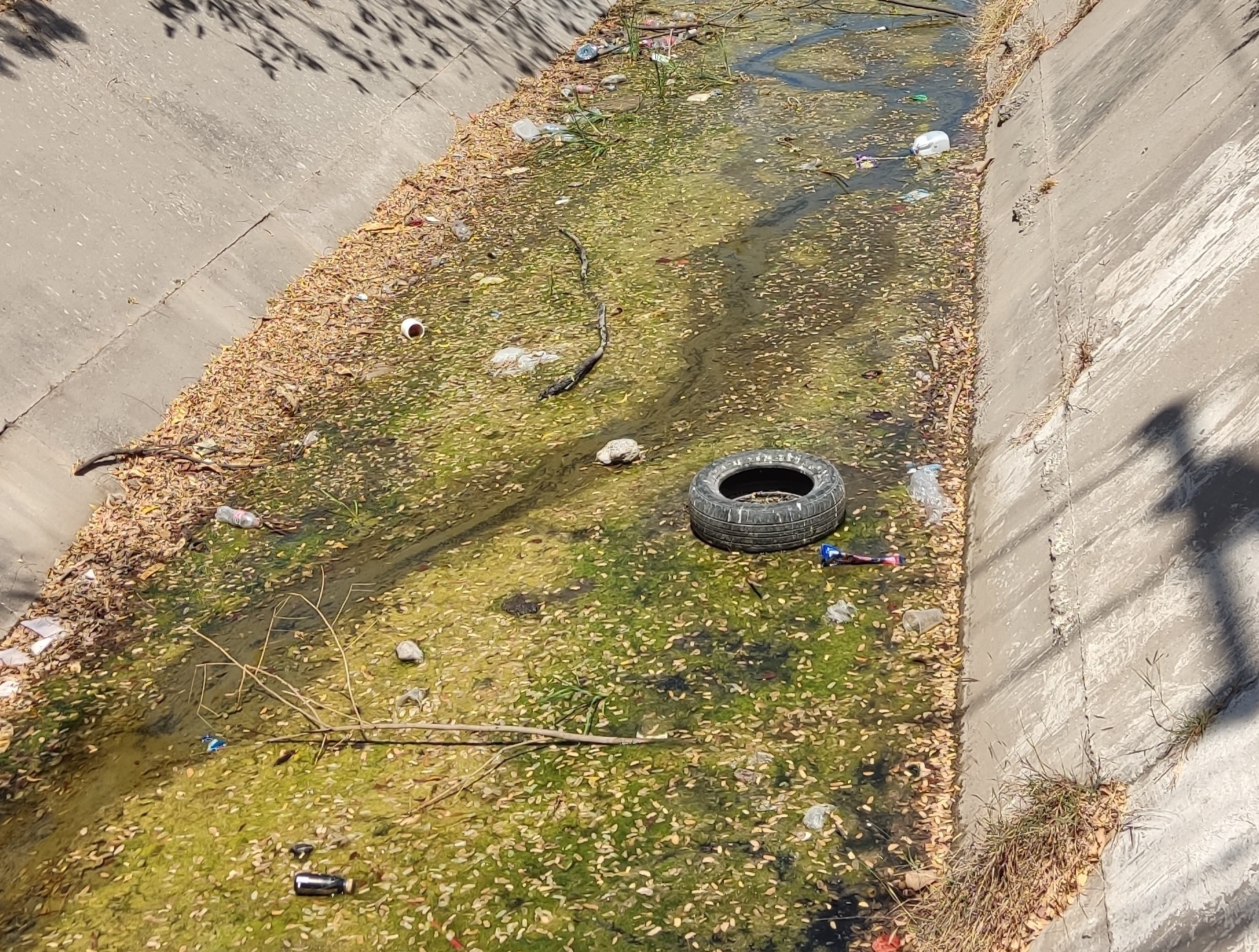 Canal revestido característico de zona urbana con contaminación por plásticos